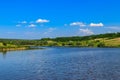 Summer landscape with beautiful lake, green meadows, hills, trees and blue sky Royalty Free Stock Photo