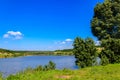 Summer landscape with beautiful lake, green meadows, hills, trees and blue sky Royalty Free Stock Photo