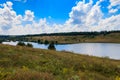 Summer landscape with beautiful lake, green meadows, hills, trees and blue sky Royalty Free Stock Photo