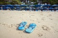 The blue slippers on the beach with white sand, against the backdrop of sun loungers with umbrellas. Royalty Free Stock Photo