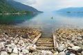 Summer landscape with the boat tied at the stony lake shore in countryside Norway.