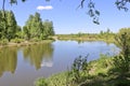 Summer landscape - A calm flat river among fields and birch groves under a blue sky. Royalty Free Stock Photo