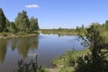 Summer landscape - A calm flat river among fields and birch groves under a blue sky. Royalty Free Stock Photo