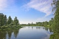 Summer landscape - calm flat river flows among forests