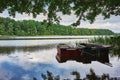 Summer landscape with calm lake and moored fishing boats under trees on the shore Royalty Free Stock Photo