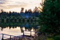 Summer landscape. Cozy wooden houses are hidden behind lush green trees on the shore of a beautiful lake on a warm summer evening Royalty Free Stock Photo