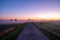 Summer Landscape with Field and Country Road Leading in the Fog. Dramatic Sky at Sunset Background. Beautiful Nature Royalty Free Stock Photo