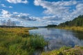 Beautiful summer landscape, forest trees are reflected in calm river water against a background of blue sky and white clouds Royalty Free Stock Photo