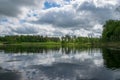 Summer landscape with lake and white cloud reflections in the water, tree silhouettes reflect in the lake water Royalty Free Stock Photo