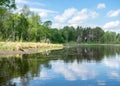 Summer landscape with lake and white cloud reflections in the water, tree silhouettes reflect in the lake water Royalty Free Stock Photo