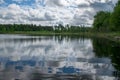 Summer landscape with lake and white cloud reflections in the water, tree silhouettes reflect in the lake water Royalty Free Stock Photo