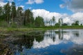 Summer landscape with lake and white cloud reflections in the water, tree silhouettes reflect in the lake water Royalty Free Stock Photo