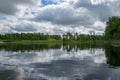 Summer landscape with lake and white cloud reflections in the water, tree silhouettes reflect in the lake water Royalty Free Stock Photo