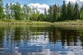 Summer landscape with lake and white cloud reflections in the water, tree silhouettes reflect in the lake water Royalty Free Stock Photo