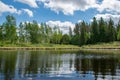 Summer landscape with lake and white cloud reflections in the water, tree silhouettes reflect in the lake water Royalty Free Stock Photo