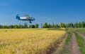 Summer landscape with an old airplane flying over an agricultural field