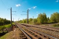 Summer landscape: old blue sky and clouds, green grass and trees, railway path road and old rusty industrial metal construction. A