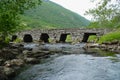 Summer landscape with an old stone bridge across the small river in rural Norway. Royalty Free Stock Photo