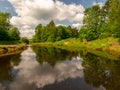 Landscape with river, green trees on shore and clouds, beautiful glare