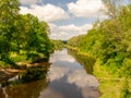 Landscape with river, green trees on shore and clouds, beautiful glare