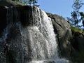 Waterfall  on the rock, pines and blue sky in  summer Kotka, Finland Royalty Free Stock Photo