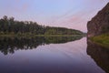 Summer landscape at sunrise. A river with rocks and forest-covered banks reflecting in it. Beauty of nature. Royalty Free Stock Photo