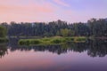 Summer landscape at sunrise. A river with trees reflected in it and a blue dawn sky with pink clouds. The beauty of the Royalty Free Stock Photo