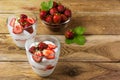 Summer layered cream dessert and ripe strawberry in glass bowl