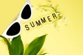 Summer layout of flowers, leaves, glasses and text with the inscription summer on a pastel yellow background. Summer