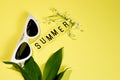 Summer layout of flowers, leaves, glasses and text with the inscription summer on a pastel yellow background. Summer