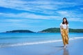 Summer lifestyle image of happy stunning woman walking on the beach of tropical island. Smiling and enjoying life in paradise.