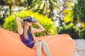 Summer lifestyle portrait of pretty girl sitting on the orange inflatable sofa and uses virtual reality headset on the Royalty Free Stock Photo
