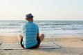 Summer lifestyle portrait of pretty young suntanned man in a hat. Enjoying life and sitting on the beach, time to travel Royalty Free Stock Photo