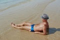 Summer lifestyle portrait of pretty young suntanned man in a hat. Enjoying life and sitting on the beach, time to travel Royalty Free Stock Photo