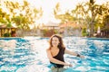 Summer lifestyle portrait of stylish woman with perfect tanned fit body, playing in pool
