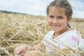 In summer  a little girl is sits on a mown wheat field near the hay Royalty Free Stock Photo