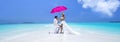 Summer love. Beautiful happy young couple in wedding clothes and pink umbrella is standing on a beach in the Maldives. Engagements Royalty Free Stock Photo