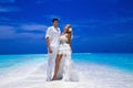 Summer love. Beautiful happy young couple in wedding clothes is standing on a beach in the Maldives. Engagements and wedding on Royalty Free Stock Photo