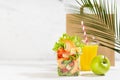 Summer lunch set with seafood salad with shrimps, orange juice, green apple in plastic pack, packet in white interior, palm leaf. Royalty Free Stock Photo