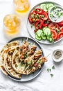 Summer lunch table - turkey skewers, tortillas, tomatoes, cucumber salad, baked sweet pepper, yogurt herb sauce and summer fruit