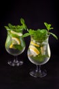 Summer mint lime refreshing cocktail mojito with rum and ice in glass on black background. Mojito cocktail on dark stone table. Royalty Free Stock Photo