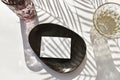 Summer mockup tableware scene. Empty blank on ceramic plate, cocktail glass on sunlit background. Royalty Free Stock Photo