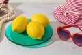 Summer modern creative background with lemons on colorful plate and beach accessories