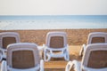 Summer morning empty sunny beach with white plastic chairs for sunbathing