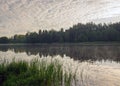 Summer morning landscape on the lake, light fog on the water surface, beautiful clouds and wonderful reflections in the lake Royalty Free Stock Photo