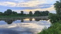 On a summer morning, the sun rises over the river behind the trees among the clouds. Willows bend their branches over the water. T Royalty Free Stock Photo