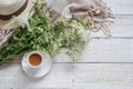 Summer morning table with a cup of coffee, wild flowers and woman`s hat