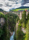 Summer mountain landscape with stream, bridge and red train.