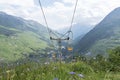 Summer mountains meadow with flowers, empty old single chairlift. Royalty Free Stock Photo