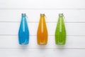 Summer multicolored refreshing drink in the bottle with chia and basil seed and fruit juice on white wooden background.